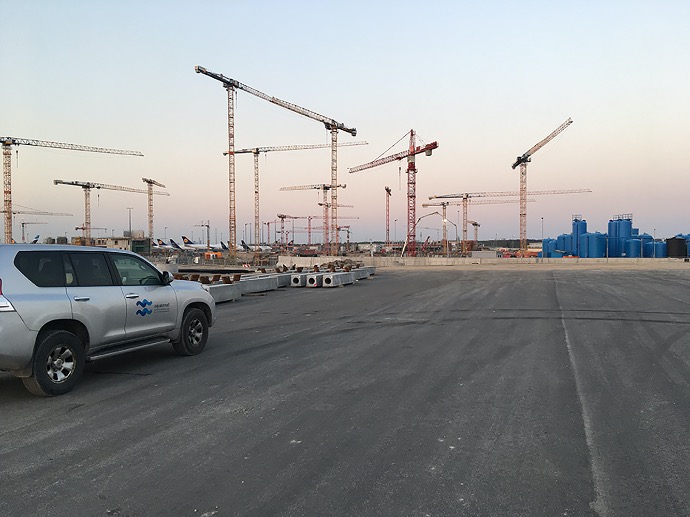 construction site on a large airport area with construction cranes in the background and a large company vehicle on the left side